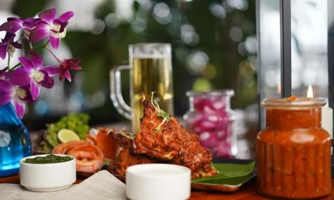 Tandoori chicken on a table surrounded by plants
